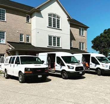 Row of Einwechter Plumbing & Heating service vans parked in front of a residential property